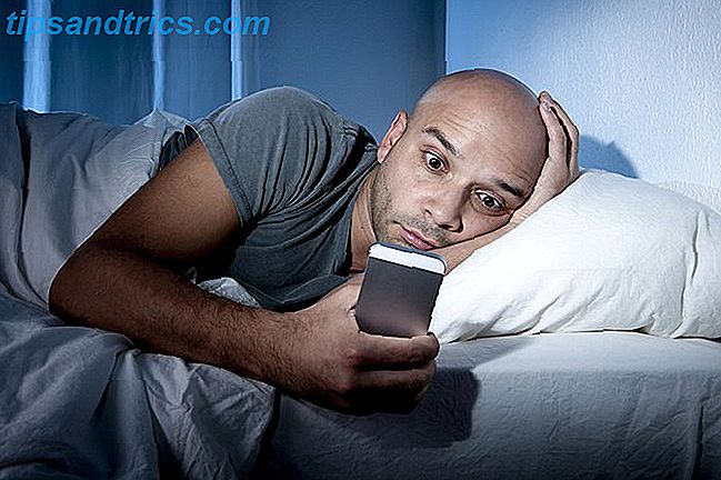mann på smarttelefon mens du er i sengen