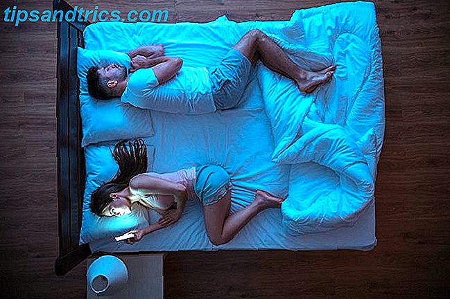 vrouw met behulp van smartphone in bed terwijl echtgenoot slaapt