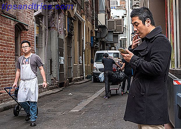 Hombre fumar cigarrillo en el teléfono en el callejón