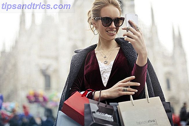 Kvinde med indkøbsposer ser på telefon